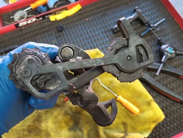 A worn derailleur stripped for service on the bench mat